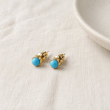 Blue Agate Stud Earrings for Women on pale grey-green linen beside a halved lime and red currants