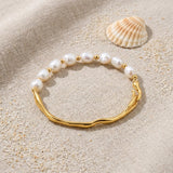 Half Pearl Gold Bracelet on raw linen beside a scallop shell and a scatter of fine sand