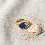 Lapis Lazuli Signet Ring on raw linen beside a scallop shell and a scatter of fine sand