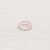 Light Pink Jade Band Ring on pale grey-green linen beside a halved lime and red currants