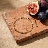 Paperclip Chain Anklet on a weathered terracotta tile with a cut fig and dark plums
