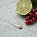 Pave Little Heart Necklace on pale grey-green linen beside a halved lime and red currants