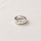 Silver Starburst Band Ring on pale grey-green linen beside a halved lime and red currants