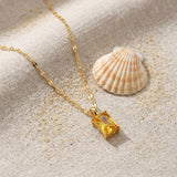 Solar Pendant Necklace on raw linen beside a scallop shell and a scatter of fine sand