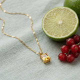 Solar Pendant Necklace on pale grey-green linen beside a halved lime and red currants