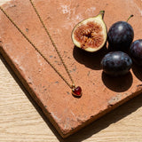 Heart Pendant Necklace on a weathered terracotta tile with a cut fig and dark plums