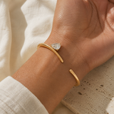 Wavy Pear Cuff worn on the wrist, gold-plated open cuff with a single pear-cut clear stone